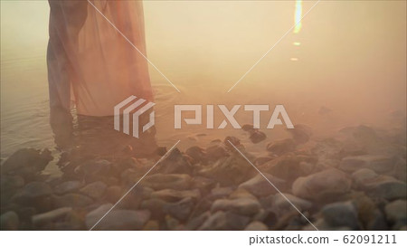Women's feet go to the water on the stones. Girl goes barefoot on the stones of a mountain river. Girl's feet in water 62091211