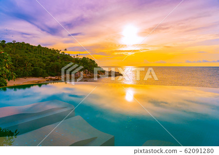 Beautiful outdoor infinity swimming pool with coconut palm tree around beach sea ocean at sunrise or sunset time 62091280