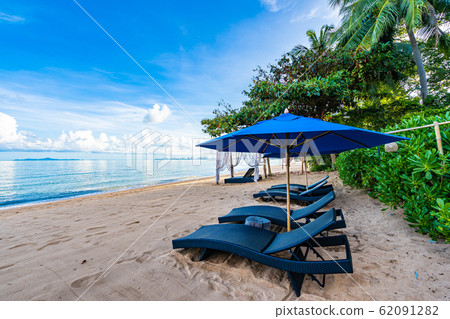 Beautiful umbrella and empty bed chair on the tropical beach and sea with white cloud blue sky background Beautiful umbrella and empty bed chair on the tropical beach and sea with white cloud blue sky background 62091282