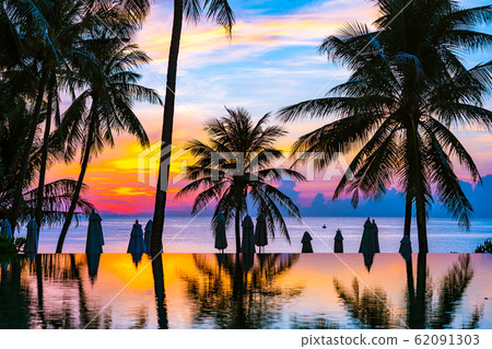 Beautiful outdoor tropical nature landscape of swimming pool in hotel resort with coconut palm tree umbrella and chair nearly sea ocean beach 62091303