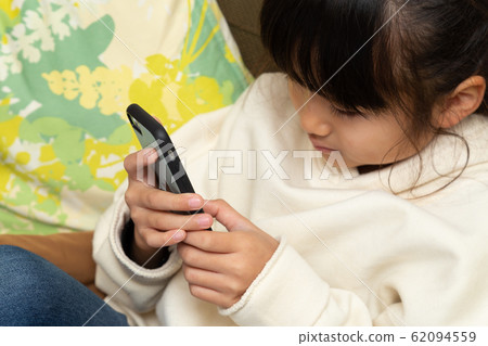 A girl watching a smartphone A girl watching a smartphone 62094559