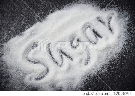 Heap of white sugar on dark background with text 62096792