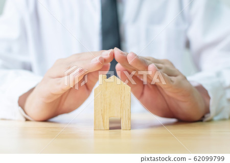 Insurance home protection concept. Man hands prevent wooden house 62099799
