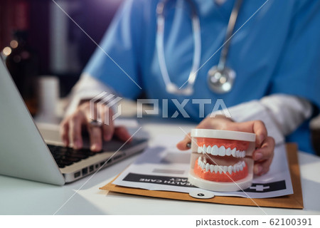 Male doctor stomatologist is working on a tablet and audio player and a digital tablet computer in a modern office in the morning at the desk. Medical Technology Concepts. Male doctor stomatologist is working on a tablet and audio player and a digital tablet computer in a modern office in the morning at the desk. Medical Technology Concepts. 62100391