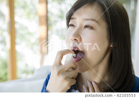 Young woman spraying throat Young woman spraying throat 62103553