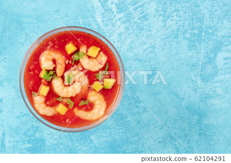 Coctel de gambas, Mexican shrimp cocktail with avocado, shot from above on a vibrant blue background with a place for text 62104291