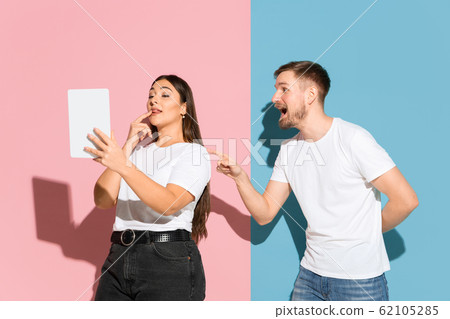 Young emotional man and woman on pink and blue background Young emotional man and woman on pink and blue background 62105285