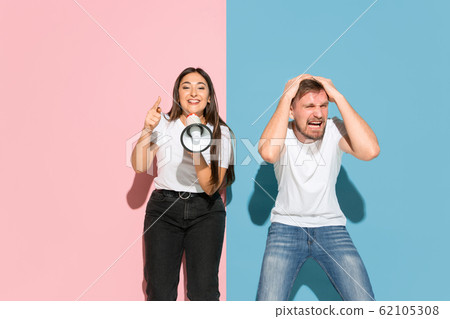Young emotional man and woman on pink and blue background Young emotional man and woman on pink and blue background 62105308
