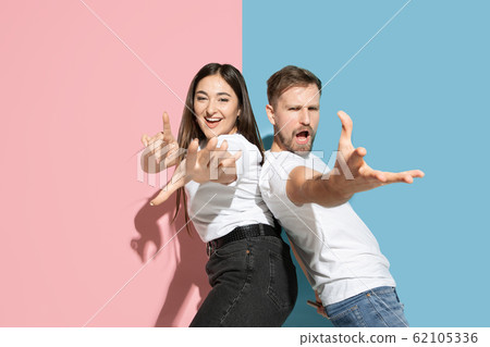 Young emotional man and woman on pink and blue background 62105336