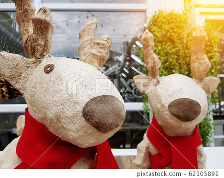 christmas holiday decorations and reindeer in front of reflect glass with light. home decorate for christmas. happy christmas two couple reindeer standing with red scarf 62105891