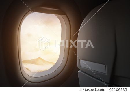travel and journey by plane concept. view of beautiful mountain and fog with golden sunlight and lens flare as seen through window of an aircraft travel and journey by plane concept. view of beautiful mountain and fog with golden sunlight and lens flare as seen through window of an aircraft 62106385