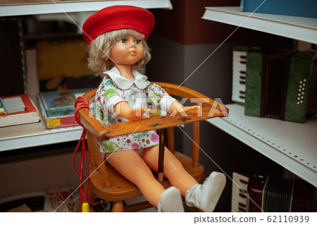 An old Soviet doll is sitting on a high chair An old Soviet doll is sitting on a high chair 62110939