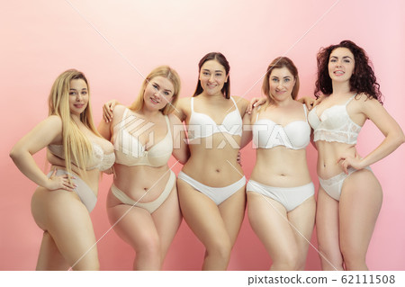 Portrait of beautiful plus size young women posing on pink background Portrait of beautiful plus size young women posing on pink background 62111508