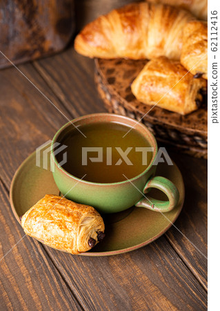 Green cup of tea with mini chocolate bun 62112416
