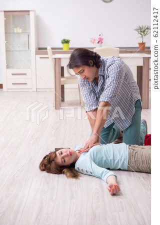Young couple in first aid concept at home 62112417