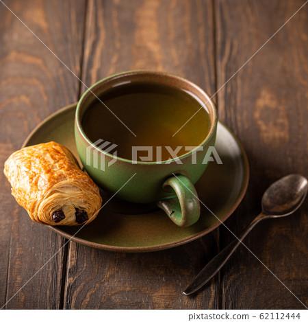 Green cup of tea with mini chocolate bun 62112444