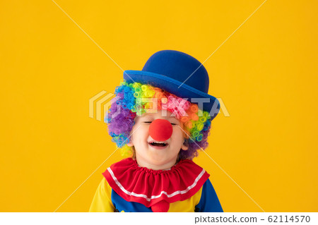 Funny kid clown playing against yellow background 62114570