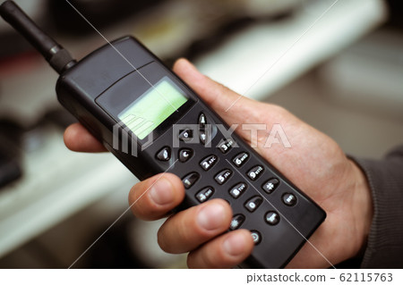 Male hand holds a black plastic vintage cell or Male hand holds a black plastic vintage cell or 62115763