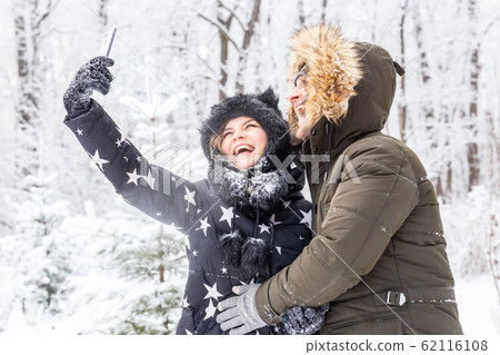 Season and relationship concept - Funny couple taking selfie in the winter time Season and relationship concept - Funny couple taking selfie in the winter time 62116108