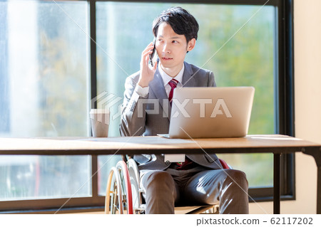 A man in a wheelchair calling on a smartphone business A man in a wheelchair calling on a smartphone business 62117202