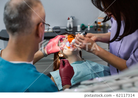 Young female patient takes a dental attendance in the dentist's office. Young female patient takes a dental attendance in the dentist's office. 62117314