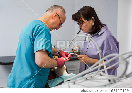 Young female patient takes a dental attendance in the dentist's office. Young female patient takes a dental attendance in the dentist's office. 62117339