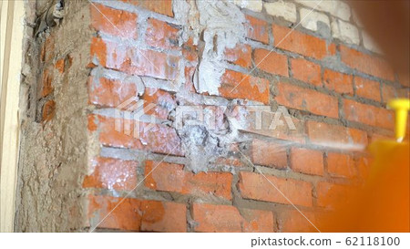 he moistening the surface before applying plaster. The process of priming a brick wall. A primer solution is applied to a brick wall using a roller thus and so to remove dust and increase adhesion 62118100