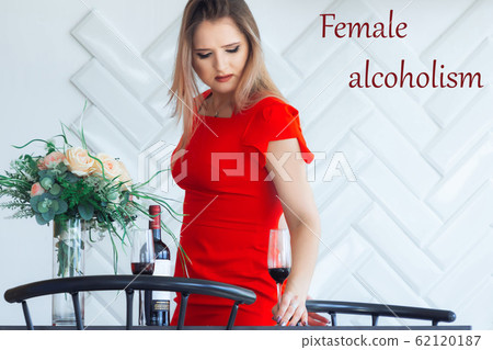 Young elegant beautiful girl picks from the table in the kitchen a glass of wine 62120187