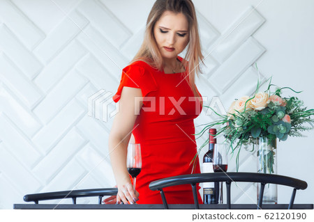 Young elegant beautiful girl picks from the table in the kitchen a glass of wine 62120190