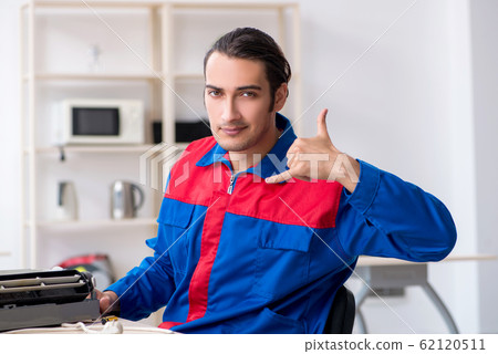 Young repairman repairing air-conditioner at warranty center Young repairman repairing air-conditioner at warranty center 62120511