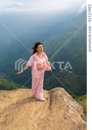 Girl enjoys a mountain view while standing on a Girl enjoys a mountain view while standing on a 62121962