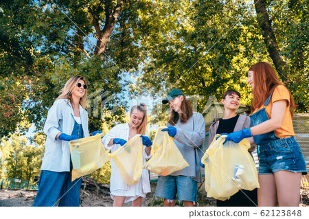 Group of activists friends collecting plastic waste on the beach. Environmental conservation. 62123848