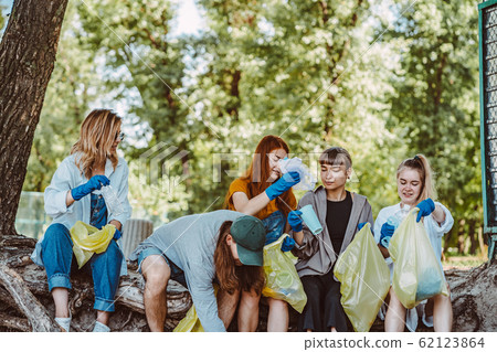 Group of activists friends collecting plastic waste at the park. Environmental conservation. 62123864