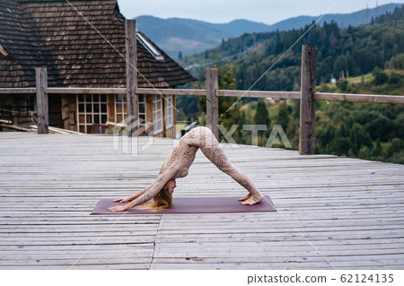 A woman practices yoga at the morning in a terrace on a fresh air. 62124135