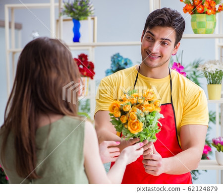 Florist selling flowers in a flower shop Florist selling flowers in a flower shop 62124879