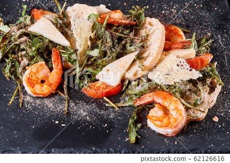 Delicious dish with grilled shrimps, squid, croutons and arugula salad and spicy fried prawns. Restaurant menu, natural and organic food concept. 62126616