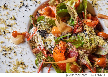 Salad with honey agaric mushroom and potato. A hearty nice salad for the festive table. Lettuce leaves, greenery, arugula, mushrooms chanterelles and dried tomatoes. 62126631