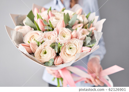 Bunch pale pink tulips and ranunculus flowers with green eucalyptus. The work of the florist at a flower shop. Bunch pale pink tulips and ranunculus flowers with green eucalyptus. The work of the florist at a flower shop. 62126901