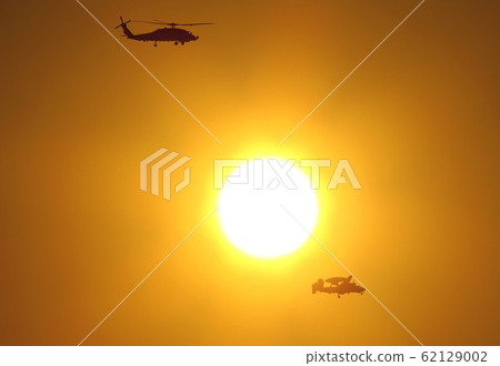 U.S. Navy SH-60B Seahawk patrol helicopter and E-2C Hawkeye early warning aircraft flying against a beautiful sunset 62129002
