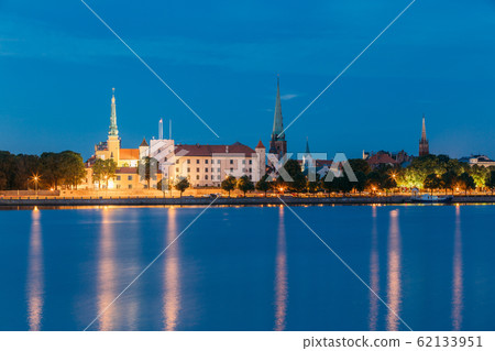 Riga, Latvia. Panoramic Picturesque Urban View Of Daugava Or Western Dvina River In Central Part Of City With Famous Landmarks In Bright Illumination Under Blue Sky In Summer Night Riga, Latvia. Panoramic Picturesque Urban View Of Daugava Or Western Dvina River In Central Part Of City With Famous Landmarks In Bright Illumination Under Blue Sky In Summer Night 62133951
