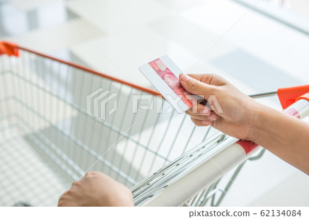 Hand holding credit card and pushing shopping trolley Hand holding credit card and pushing shopping trolley 62134084