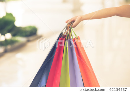 Woman hand holding colorful shopping bags on blurry background 62134587