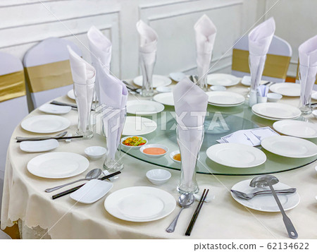 Beautiful banquet table setting with white tableware and glasses Beautiful banquet table setting with white tableware and glasses 62134622