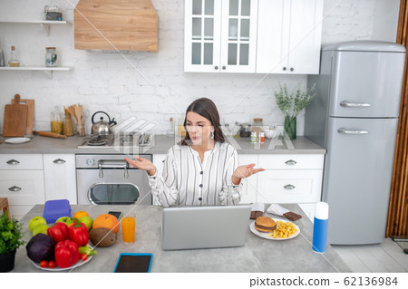 Dark-haired woman in a striped blouse thinking about dieting 62136984
