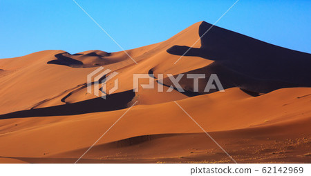 Beautiful landscape with red huge sand dunes at sunset in desert. Sossusvlei, Namib Naukluft National Park, Namibia. Stunning natural geometry without people 62142969