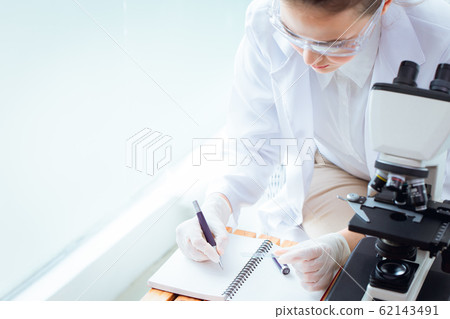 Scientist doctor taking note or writing memo on working day in virus research Scientist doctor taking note or writing memo on working day in virus research 62143491