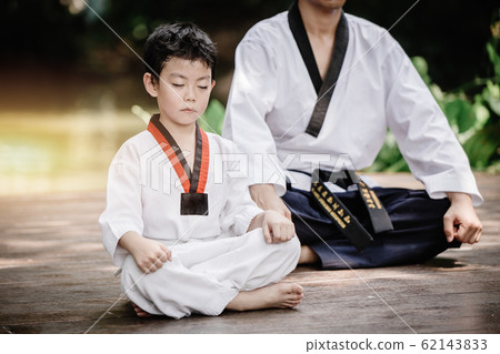 Fighter kid in Taekwondo uniform sitting concentration for training  62143833