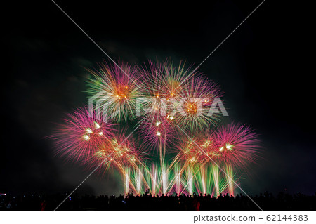 Crowd looks holiday fireworks in dark evening sky. Crowd looks holiday fireworks in dark evening sky. 62144383