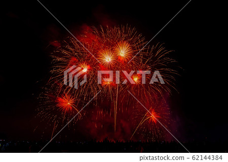 Crowd looks holiday fireworks in dark evening sky. Crowd looks holiday fireworks in dark evening sky. 62144384