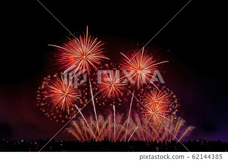 Crowd looks holiday fireworks in dark evening sky. Crowd looks holiday fireworks in dark evening sky. 62144385